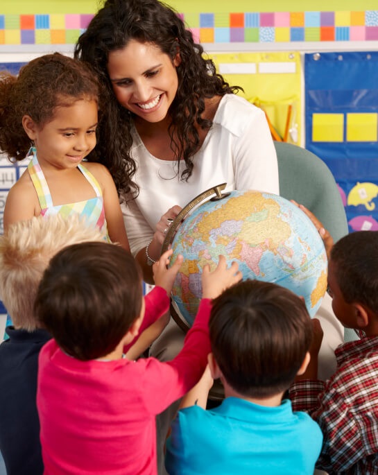 Preschool teacher and students looking at world globe