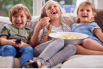 Children enjoying popcorn on couch